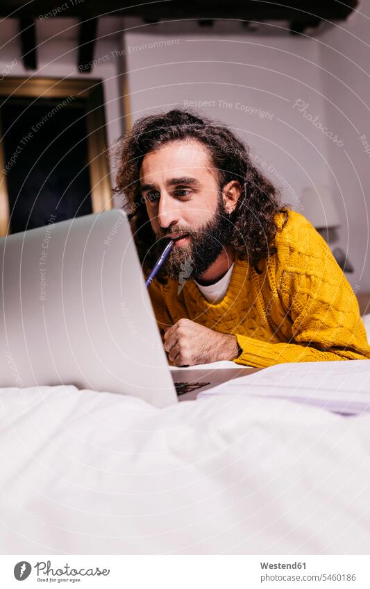 Junger Mann liegt im Bett zu Hause mit Laptop Notebook Laptops Notebooks Männer männlich Zuhause daheim Betten liegen liegend Computer Rechner Erwachsener