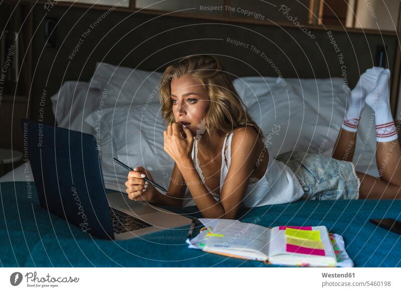 Frau auf dem Bett liegend, mit Laptop Hotelzimmer blond Laptop benutzen Mensch Computer Erwachsener Schlafzimmer Organisation Erreichbarkeit Konzentration Abend