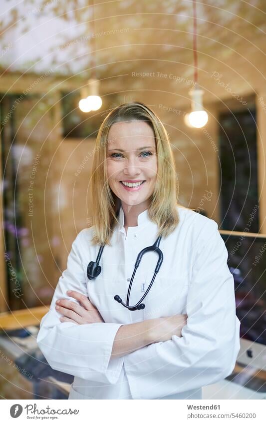 Porträt einer lächelnden Ärztin mit Stethoskop hinter Fensterscheibe Fensterscheiben Frau weiblich Frauen Stethoskope Portrait Porträts Portraits Aerztin