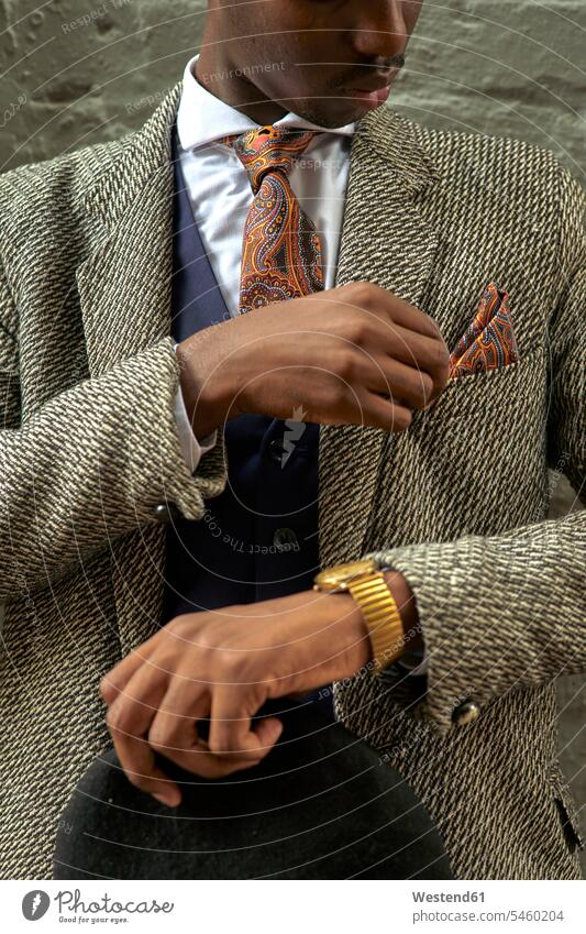 Stilvoller Geschäftsmann, der eine Baskenmütze hält und sein Taschenquadrat kontrolliert Leute Menschen People Person Personen Afrikanisch