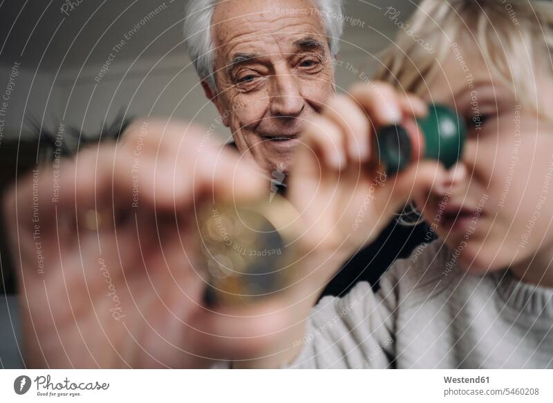 Uhrmacher und sein Enkel prüfen gemeinsam die Uhr Europäer zwei Personen Junge 10-11 Jahre Senior 70-80 Jahre Freizeitkleidung Textfreiraum Zuhause Deutschland