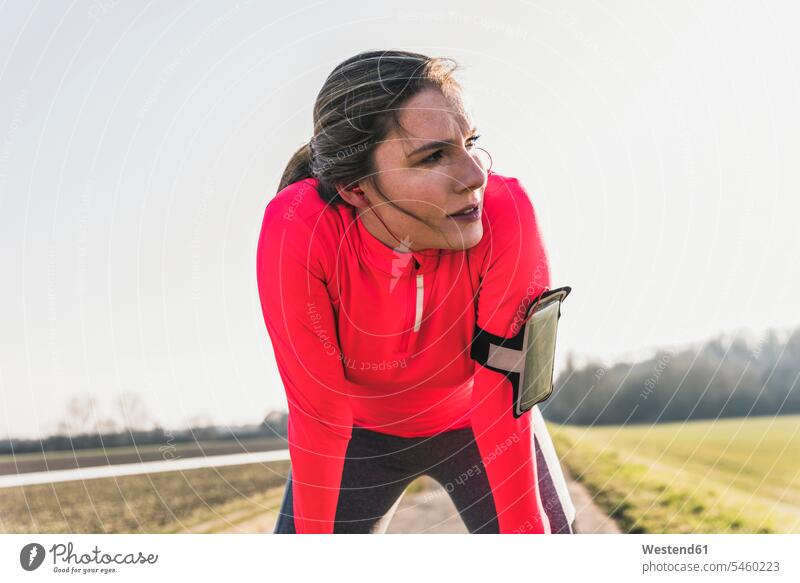 Junge Frau, die eine Pause vom Laufen auf dem Land einlegt ländlich auf dem Lande Joggen Jogging weiblich Frauen Fitness fit Gesundheit gesund Sport Erwachsener