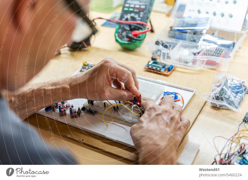 Leitender Mann, der in seiner Werkstatt an elektronischen Schaltungen arbeitet Job Berufe Berufstätigkeit Beschäftigung Jobs Rechner Arbeit Reparatur Anschluss