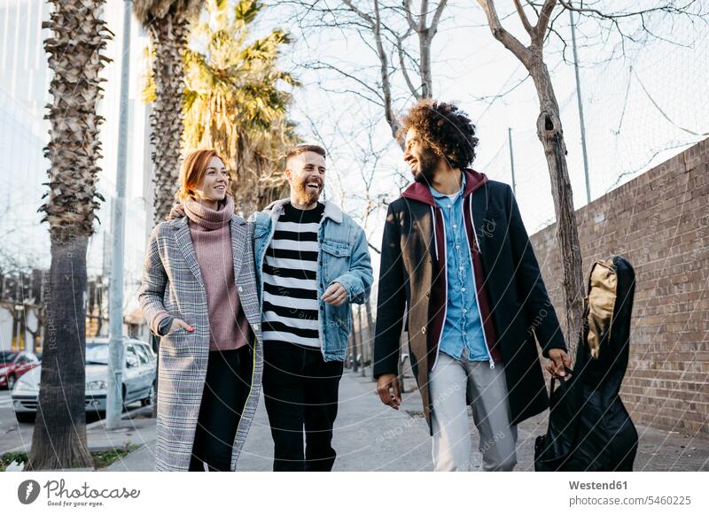 Drei glückliche Freunde beim Spaziergang in der Stadt Glück glücklich sein glücklichsein gehen gehend geht Freundschaft Kameradschaft Ziegelmauer Ziegelwand