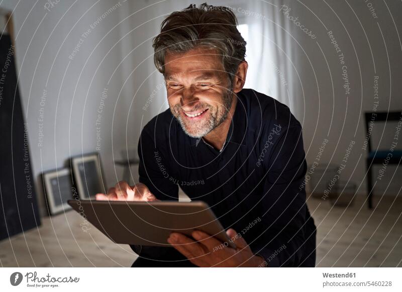 Porträt eines lächelnden, reifen Mannes, der zu Hause Spaß mit einem digitalen Tablet hat geschäftlich Geschäftsleben Geschäftswelt Geschäftsperson