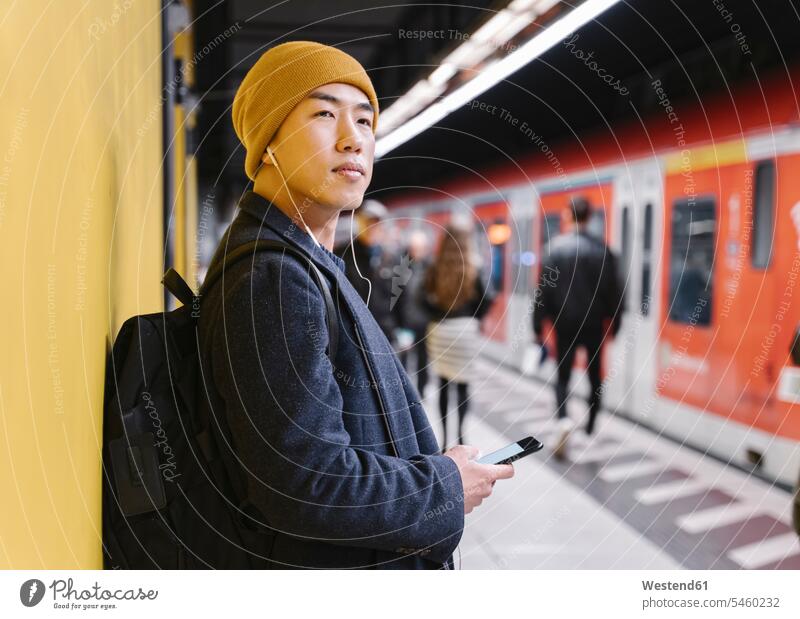 Stilvoller Mann mit gelbem Hut und Kopfhörern in der U-Bahn-Station Touristen Rucksäcke Jacken Transport Transportwesen Bahnen Subway U-Bahnen Ubahn Ubahnen