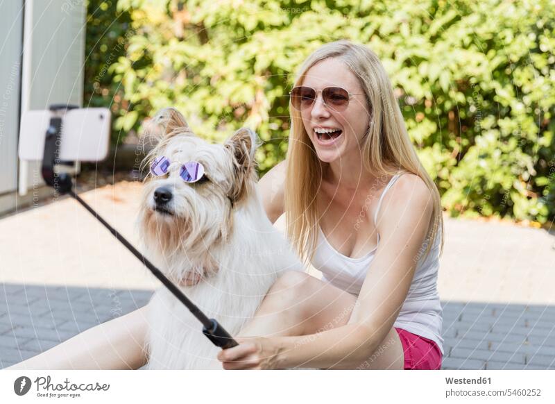 Glückliche Frau, die ein Selfie mit ihrem Hund macht und eine Sonnenbrille trägt Deutschland verspielt spielerisch Drahtlose Technologie drahtlose Verbindung