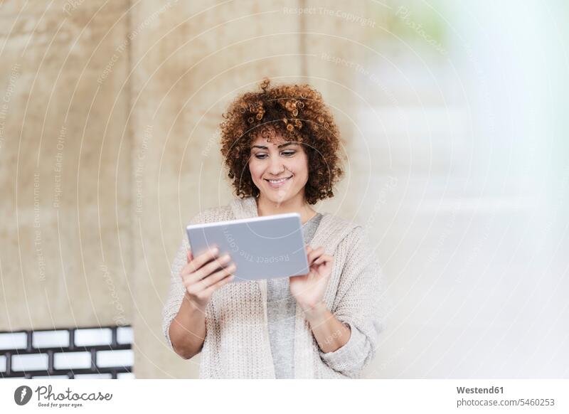 Lächelnde Frau mit Tablet an Betonwand Tablet Computer Tablet-PC Tablet PC iPad Tablet-Computer weiblich Frauen Betonwände Betonwaende lächeln Rechner