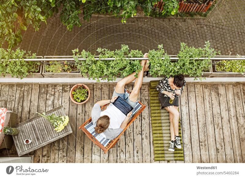 Junges Paar entspannt auf dem Balkon im Sommer, Mann benutzt Tablet Pflanze Pflanzenwelt Flora Tablet Computer Tablet-PC Tablet PC iPad Tablet-Computer Freizeit