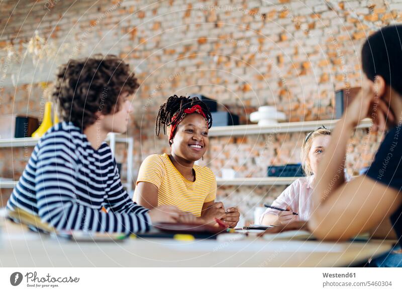 Junge Menschen sitzen zusammen am Tisch und unterhalten sich Europäer Schwarzer vier Personen junge Frau 20-25 Jahre junger Mann 18-19 Jahre Regal modern