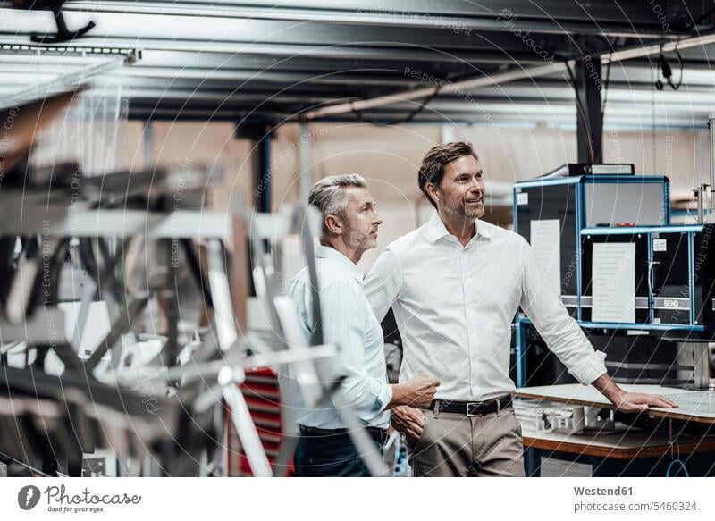 Reifer Kollege diskutiert mit lächelndem Manager, während er in der Fabrik an den Fertigungsmaschinen steht Farbaufnahme Farbe Farbfoto Farbphoto Deutschland