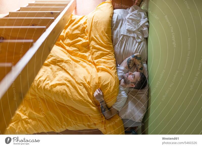 Tätowierter Mann im Bett liegend, Holzleiter Leute Menschen People Person Personen Europäisch Kaukasier kaukasisch erwachsen Erwachsene Männer männlich jung