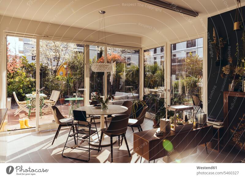 Esszimmerbereich mit Sonnenschein von der Terrasse im Frühling Fensterscheiben Stuehle Stühle Tische Esstische Jahreszeiten Frühjahr Lenz daheim zu Hause leere