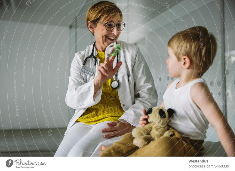 Peditricianer mit Fingerpuppen und Kleinkind in der medizinischen Praxis Leute Menschen People Person Personen Europäisch Kaukasier kaukasisch 2 2 Menschen