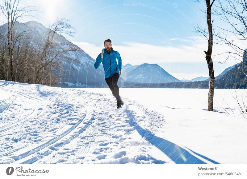 Deutschland, Bayern, sportlicher Mann läuft durch Schnee im Winter Männer männlich laufen rennen winterlich Winterzeit Erwachsener erwachsen Mensch Menschen