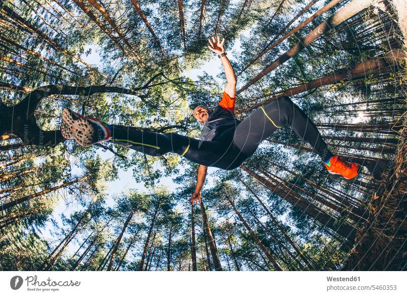 Erwachsener Mann springt im Wald gegen Bäume Farbaufnahme Farbe Farbfoto Farbphoto Spanien Außenaufnahme außen draußen im Freien Tag Tageslichtaufnahme