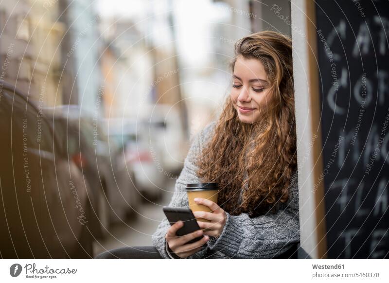 Teenager-Mädchen trinkt Kaffee, liest Textnachrichten hübsch Teenagerin junges Mädchen Teenagerinnen weiblich junge Frau lesen Lektüre SMS Smartphone iPhone