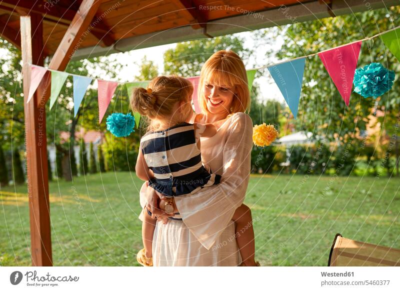 Glückliche Mutter trägt ihre Tochter auf einer Gartengeburtstagsfeier Feier Fest Festlichkeit Feiern Festlichkeiten Feste Töchter Mami Mutti Mütter Mama