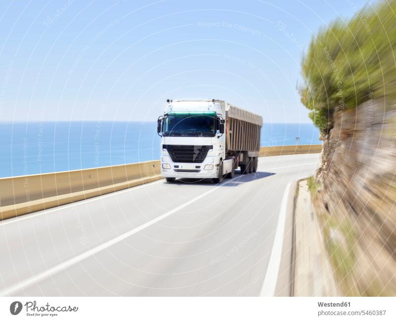 Lastwagen fahren entlang der Jersey-Barriere der Küstenautobahn, Sitges, Barcelona, Spanien Außenaufnahme außen draußen im Freien Tag Tageslichtaufnahme