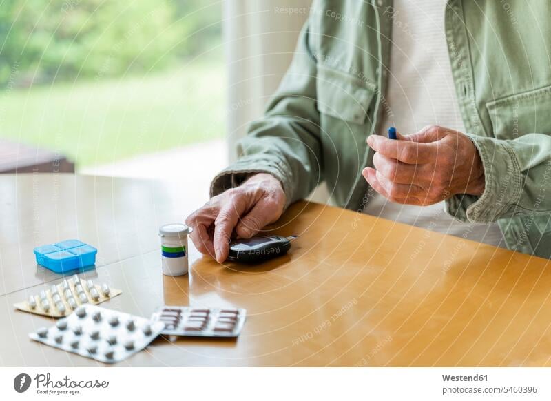 Mittelteil eines älteren diabetischen Mannes im Ruhestand, der sich selbst untersucht, während er am Tisch sitzt Farbaufnahme Farbe Farbfoto Farbphoto