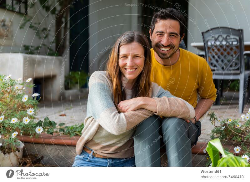 Lächelndes Paar sitzt auf Stufen gegen Bauernhaus Farbaufnahme Farbe Farbfoto Farbphoto Spanien Freizeitbeschäftigung Muße Zeit Zeit haben Freizeitkleidung