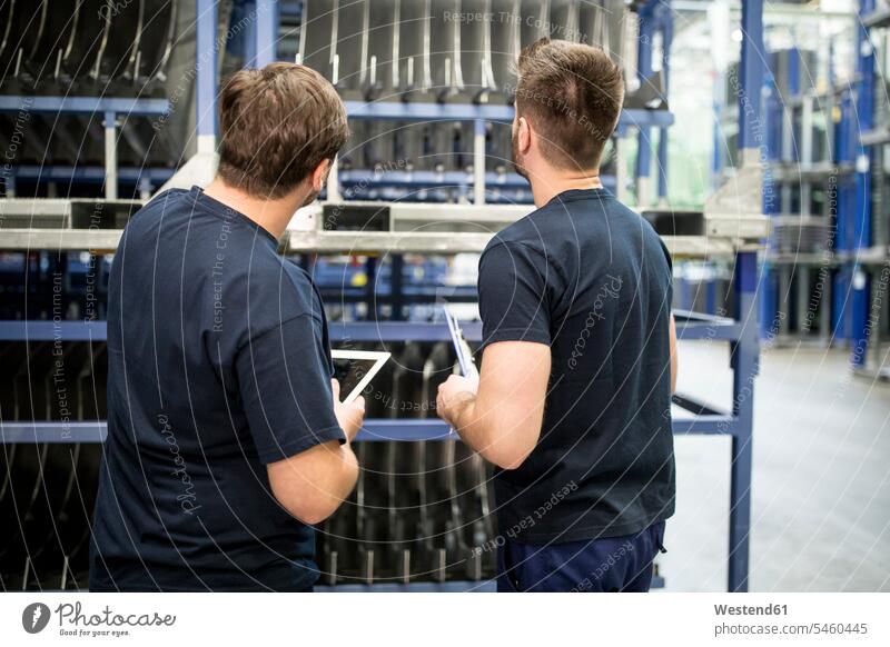 Zwei Arbeiter mit Zwischenablage und Tablette im Fabriklager Arbeitskollege Arbeitskollegen Kollege Job Berufe Berufstätigkeit Beschäftigung Jobs T-Shirts