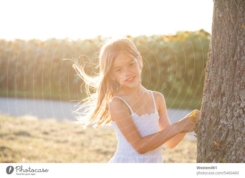 Mädchen am Sommerabend auf Baumstamm stehend Blickkontakt Augenkontakt Stamm Stämme Baumstämme Bäume Baeume Freude freuen Sommerzeit sommerlich Wind Brisen