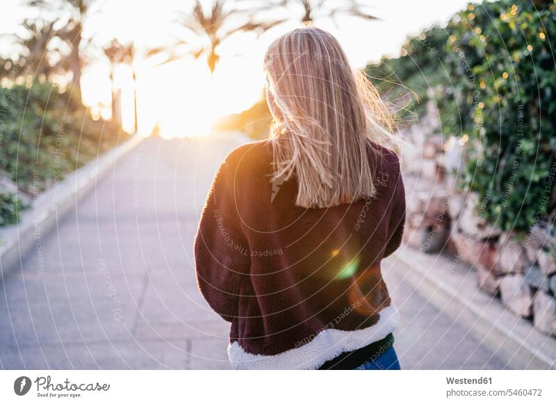 Junge Frau in Pelzjacke geht bei Sonnenuntergang auf der Straße Jacken gehend abends rote roter rotes Muße Individuell Lifestyles außen draußen im Freien