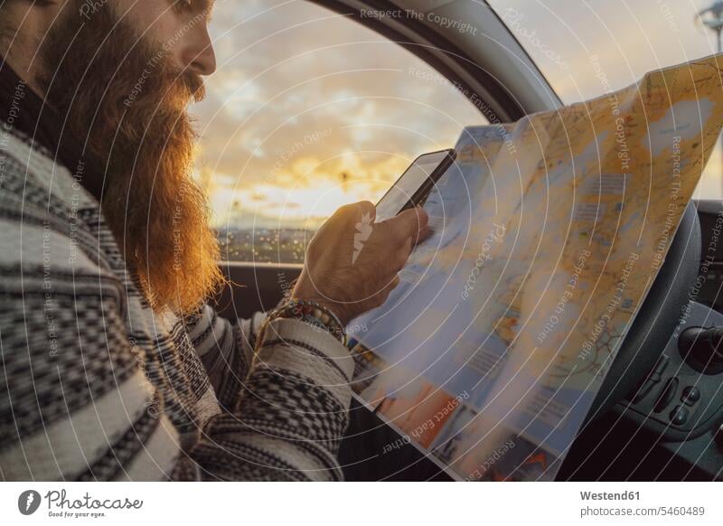 Mann benutzt Smartphone im Auto, schaut auf Karte für Wegbeschreibung Männer männlich Landkarte Landkarten erkunden Erforschung Erkundung erforschen Island