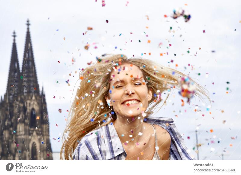 Deutschland, Köln, Porträt einer glücklichen blonden Frau zwischen einem Konfettiregen blonde Haare blondes Haar Portrait Porträts Portraits Confetti weiblich