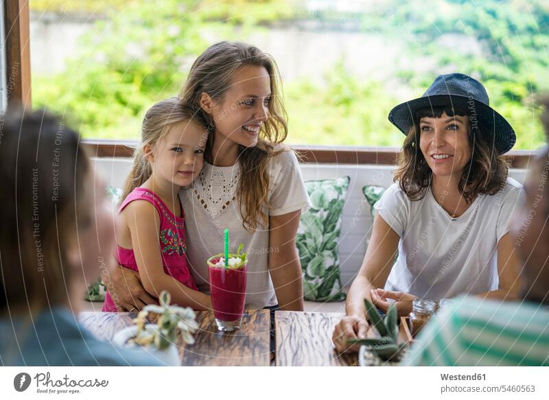 Frau mit Mädchen auf dem Schoß lächelt ihren Freund im Café an Freunde weiblich Cafe Kaffeehaus Bistro Cafes Cafés Kaffeehäuser glücklich Glück glücklich sein