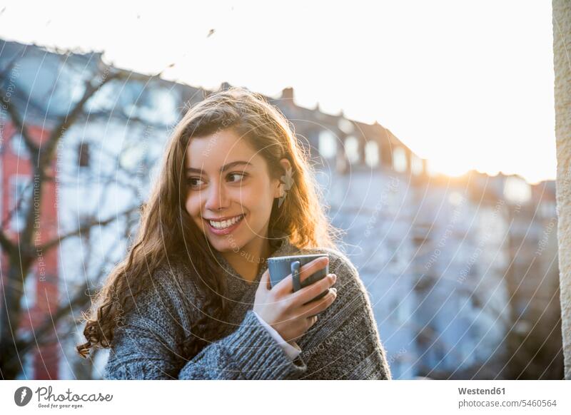 Porträt eines lachenden Teenagers mit Kaffeebecher auf dem Balkon in der Dämmerung Balkone Teenagerin junges Mädchen Teenagerinnen weiblich junge Frau Becher