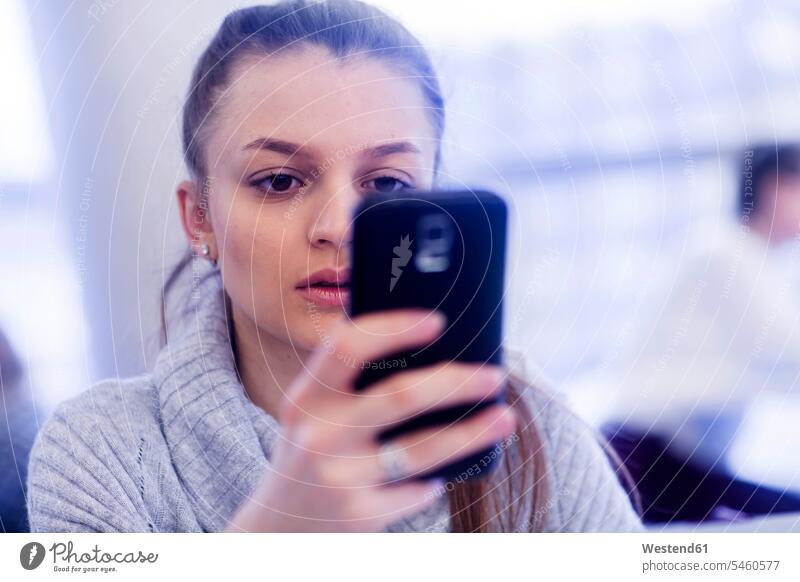 Porträt einer jungen Frau, die ein Smartphone benutzt benutzen benützen Portrait Porträts Portraits Büro Office Büros weiblich Frauen iPhone Smartphones