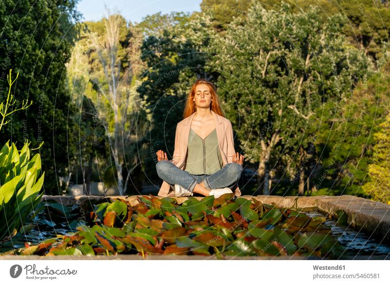 Junge rothaarige Frau meditiert in einem Park Leute Menschen People Person Personen Europäisch Kaukasier kaukasisch erwachsen Erwachsene Frauen weiblich jung