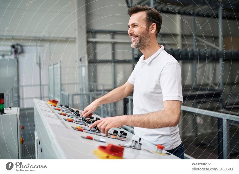 Lächelnder Mann, der ein Bedienfeld in einer Fabrik bedient Job Berufe Berufstätigkeit Beschäftigung Jobs Arbeiter Techniken Technologie Techniker freuen