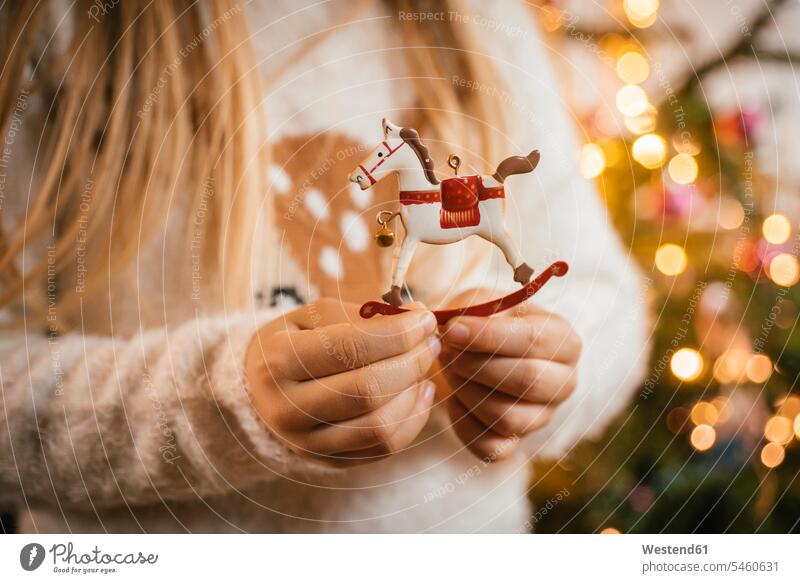 Den Weihnachtsbaum schmücken, Mädchen hält ein Schaukelpferd aus Ziermetall Leute Menschen People Person Personen Europäisch Kaukasier kaukasisch 1 Ein