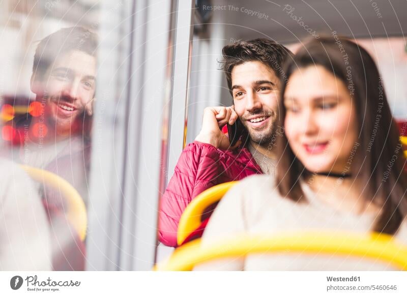 Großbritannien, London, Porträt eines lächelnden jungen Mannes am Telefon in einem Bus telefonieren anrufen Anruf telephonieren Portrait Porträts Portraits