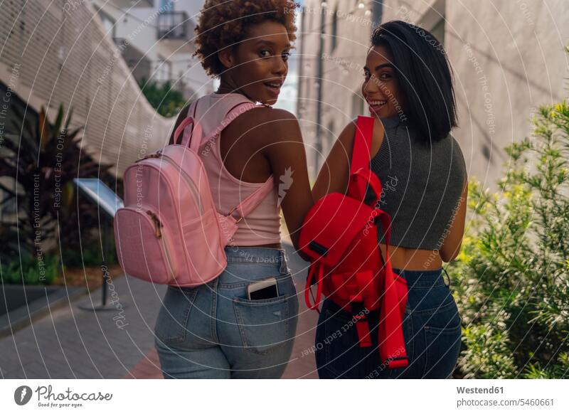 USA, Florida, Miami Beach, Rückansicht von zwei glücklichen Freundinnen beim Spaziergang in der Stadt staedtisch städtisch gehen gehend geht Glück