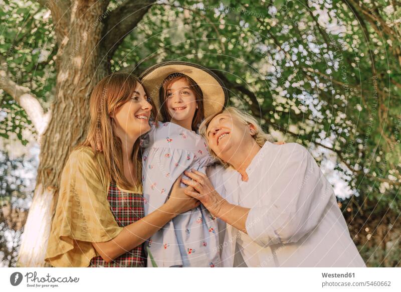 Glückliche Familie umarmt Mädchen mit Hut gegen Baum im Hof Farbaufnahme Farbe Farbfoto Farbphoto Spanien Freizeitbeschäftigung Muße Zeit Zeit haben