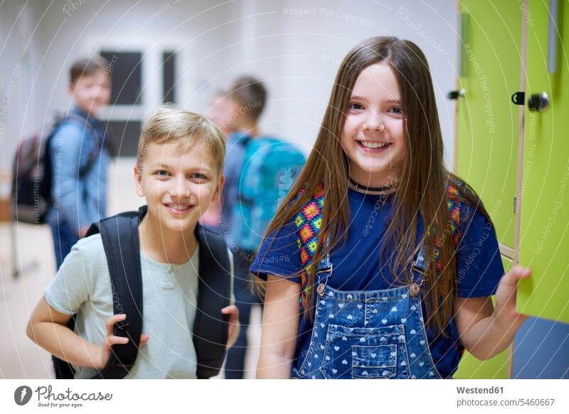 Porträt eines lächelnden Schuljungen und eines lächelnden Schulmädchens an Schließfächern in der Schule Schüler Spind Portrait Schülerin Schulkind Bildung