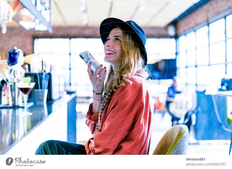 Lächelnde Frau mit Smartphone in einem Café weiblich Frauen Cafe Kaffeehaus Bistro Cafes Cafés Kaffeehäuser lächeln Handy Mobiltelefon Handies Handys