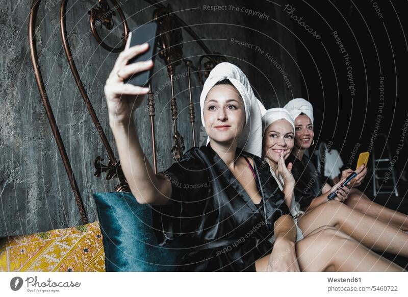 Drei Frauen mit Handtüchern um ihre Köpfe auf dem Bett machen ein Selfie Freundinnen weiblich Selfies Kopf Betten Handtuch Handtuecher Freunde Freundschaft