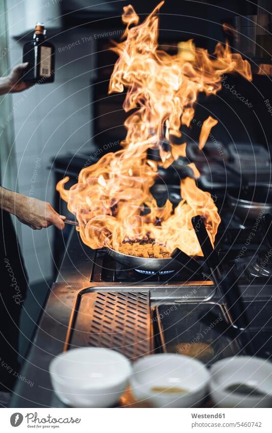 Koch, der ein Flammengericht am Gasherd in der Restaurantküche zubereitet Job Berufe Berufstätigkeit Beschäftigung Jobs Gastronomie Koeche Kuechenchef