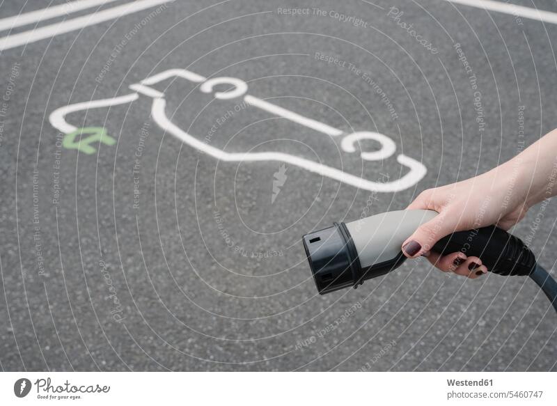 Deutschland, Hand einer Frau, die den Stecker einer Ladestation für Elektrofahrzeuge hält Außenaufnahme außen draußen im Freien Tag Tageslichtaufnahme