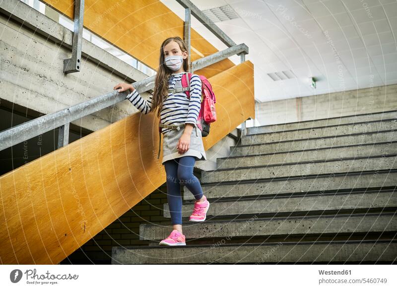 Mädchen mit Maske in der Schule geht die Treppe hinunter Schüler gehen Gesundheit Schutz Sicherheit Innenaufnahme Portrait Tag Blickkontakt Schülerin