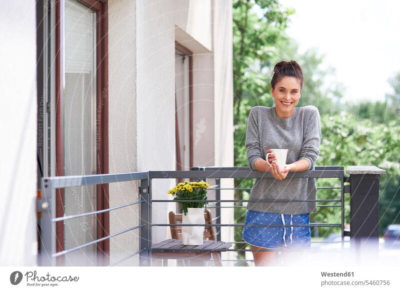 Junge Frau trinkt Morgenkaffee auf dem Balkon stehen stehend steht junge Frau junge Frauen morgens früh Frühe Balkone trinken Kaffee weiblich Erwachsener