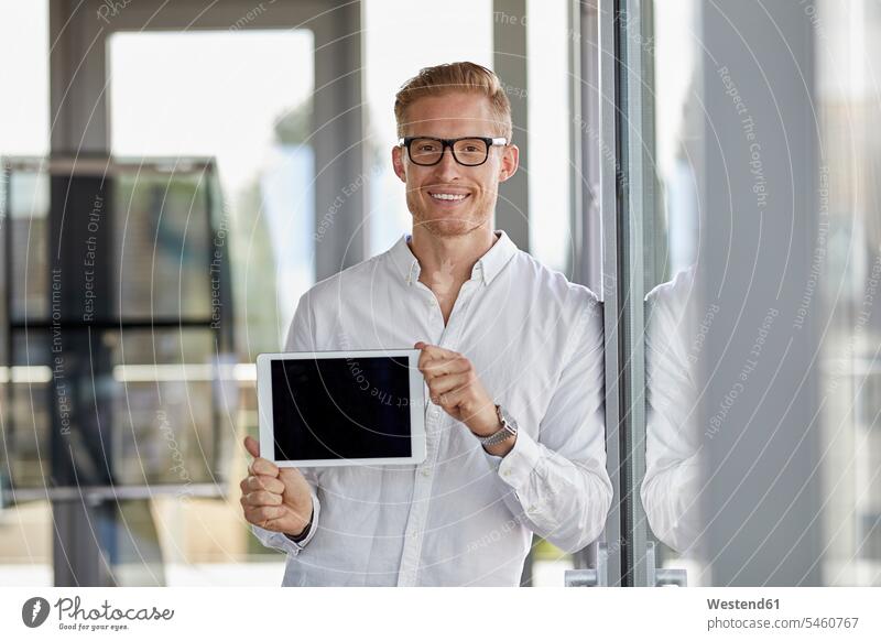 Porträt von lächelnden Geschäftsmann zeigt Tablette am Fenster im Büro Office Büros Portrait Porträts Portraits Tablet Computer Tablet-PC Tablet PC iPad
