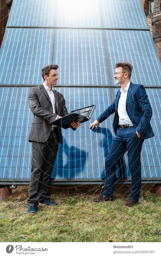 Zwei Geschäftsleute im Gespräch an Solarzellen Sonnenkollektor Photozellen Sonnenzellen lichtelektrische Zellen Sonnenkollektoren sprechen reden Solarpanel