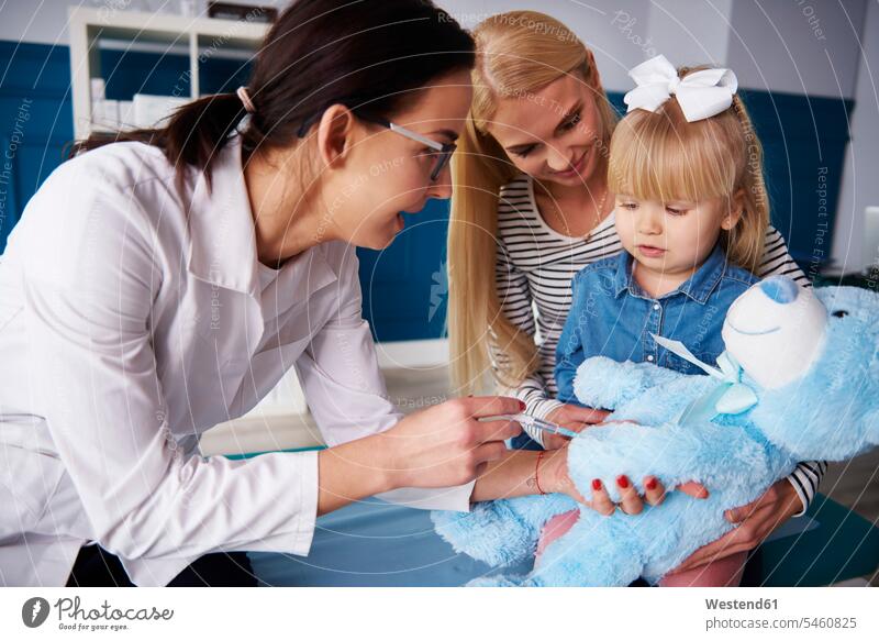 Arzt und Mädchen mit Mutter impfen Teddy in der medizinischen Praxis Ärztin Aerztin Ärztinnen Doktorinnen Aerztinnen untersuchen prüfen weiblich Teddies