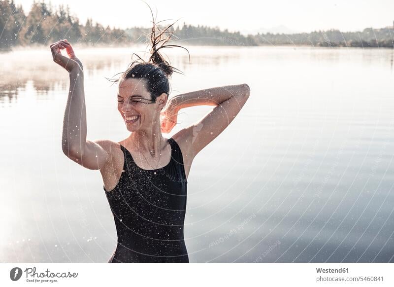 Fröhliche Frau im schwarzen Badeanzug an einem See im Morgennebel Badebekleidung Badeanzuege Badeanzüge früh Frühe begeistert Enthusiasmus enthusiastisch